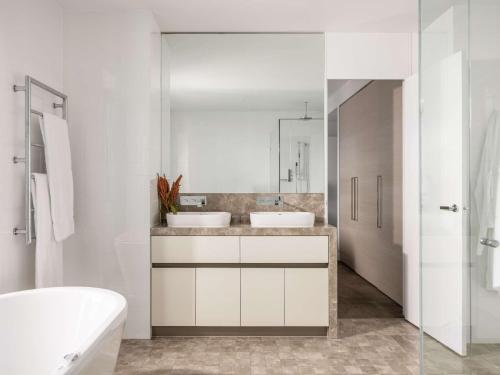 a white bathroom with two sinks and a mirror at Peppers Soul Surfers Paradise in Gold Coast