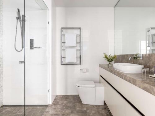 a white bathroom with a toilet and a sink at Peppers Soul Surfers Paradise in Gold Coast