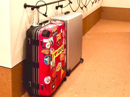 two suitcases stacked against a wall with stickers on them at HOTEL minimumms女性専用カプセルホテルWomen only hotel in Naha