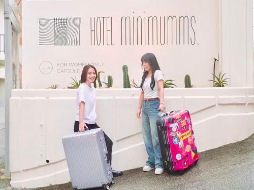 two girls standing with their luggage in front of a store at HOTEL minimumms女性専用カプセルホテルWomen only hotel in Naha