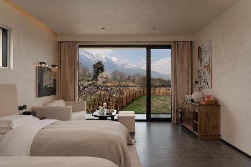 a hotel room with two beds and a large window at 不晚里予日照金山丨雪山全景度假酒店白沙古镇店 in Baisha