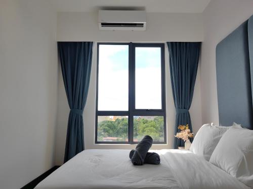 a cat laying on a bed in front of a window at Vetro11 Beside QEH1 by JUNE Homestay in Kota Kinabalu