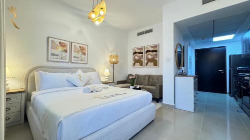 a bedroom with a large white bed and a living room at Al Reef Luxury Studio - Elegant Stay Near Al Reef Community Park in Abu Dhabi