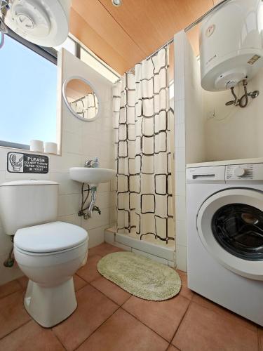 a bathroom with a toilet and a sink and a washing machine at Corner view 4 in Marsaskala
