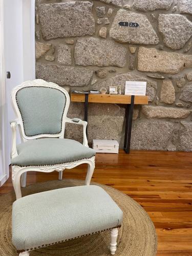 two chairs and a table in a room with a stone wall at Botica Guesthouse in Espinho