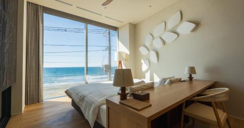 a bedroom with a desk and a view of the ocean at UMITO VILLA KAMAKURA Zaimokuza in Kamakura