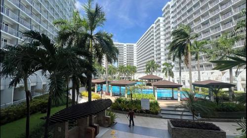a person walking down a sidewalk in front of a building at Kathys Crib 2Bedroom MOA View at Shell Residence in Manila