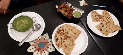 a table with plates of food and a bowl of soup at Sunrise Homestay Agra Near Taj Mahal in Agra
