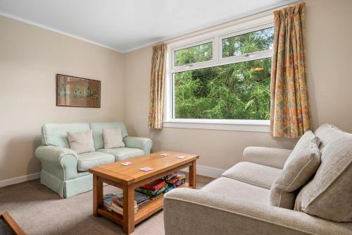 a living room with a couch and a table and a window at Charming 2-Bed Cottage on Tranquil Raera Farm in Kilninver
