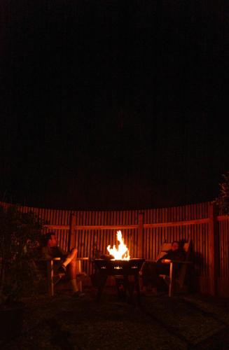 a group of people sitting around a fire at night at Luxury Glamping Tali Pod Escape with Private HotTub in Pembroke