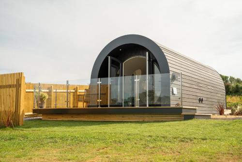 a building with a large window on top of a field at Luxury Glamping Tali Pod Escape with Private HotTub in Pembroke