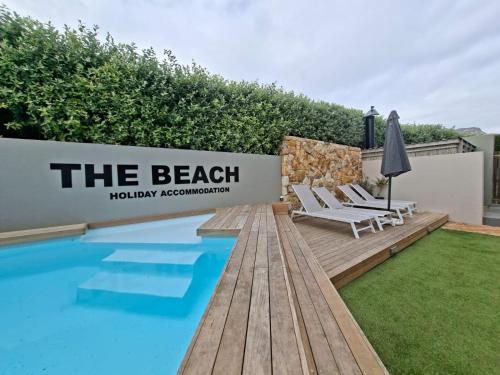 a backyard with a swimming pool and chairs next to a fence at Beach Holiday Accommodation in Hout Bay