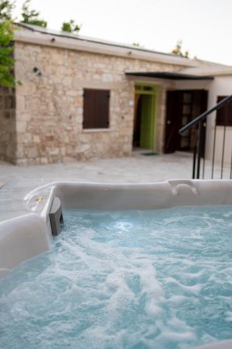 a hot tub in front of a house at Droshia Traditional Homes, COCO-MAT Full Experience in Drousha