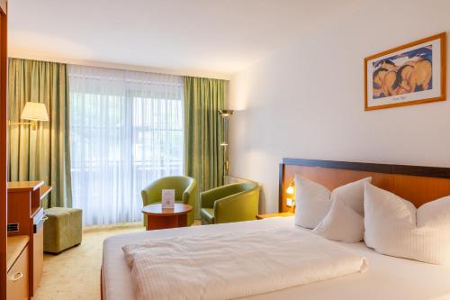 a hotel room with a bed and a chair at Königshof Hotel Resort in Oberstaufen