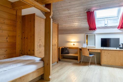 a bedroom with a bed and a desk and a television at Königshof Hotel Resort in Oberstaufen
