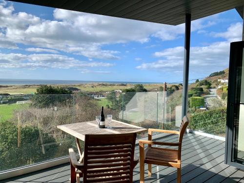 a table and chairs on a deck with a large window at Bodwennol - a stunning house! in Aberdyfi