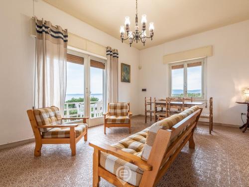 Una sala de estar con un sofá y sillas y ventanas. en House Minerva, en San Vero Milis