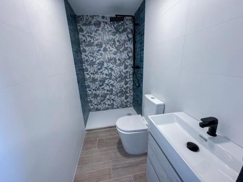 a white bathroom with a toilet and a shower at Boliches 71 Hostel in Fuengirola