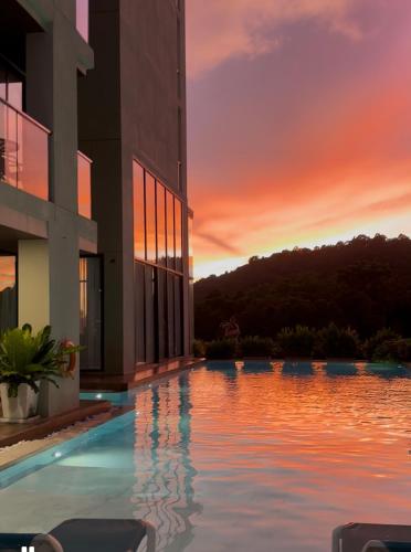 a building with a pool with a sunset in the background at The Viva Patong in Patong Beach