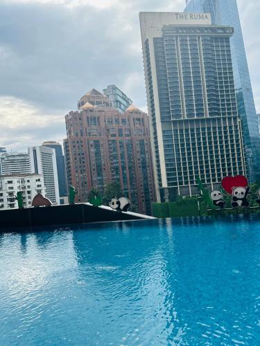 a large pool of blue water in front of buildings at KL suites by Nomad in Kuala Lumpur