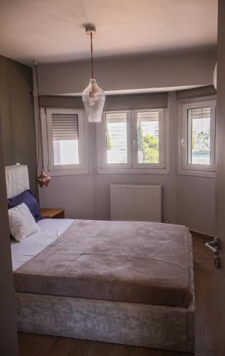 a bedroom with a large bed with two windows at Athenean Coastal Getaway in Athens