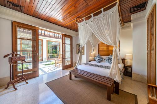 a bedroom with a bed with a canopy at Jimbaran Beach Villas by Nakula in Jimbaran