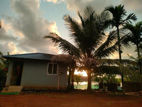 a house with palm trees in front of the sunset at AURA PARK STAY - Kumta in Kumta