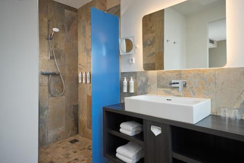 a bathroom with a sink and a shower at Haven Hotel Rotterdam, Curio Collection by Hilton in Rotterdam