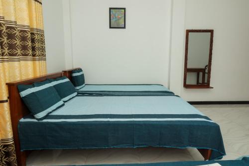 a bedroom with a bed with blue sheets and a mirror at Ever Top Resort Kithulgala in Kitulgala