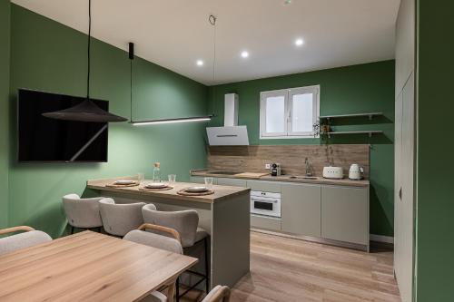 a kitchen with green walls and a table and chairs at Queens Bernabéu in Madrid