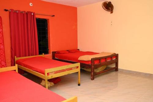 a room with two beds with red walls and a window at AURA PARK STAY - Kumta in Kumta