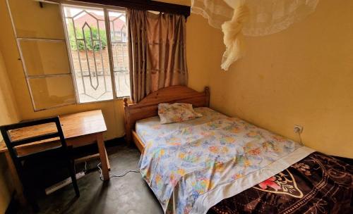 a bedroom with a bed and a desk and a window at Bonnie's Homestay in Gasanze