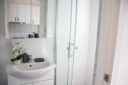 een witte badkamer met een wastafel en een douche bij Cozy City House in the Heart of Paddington in Sydney