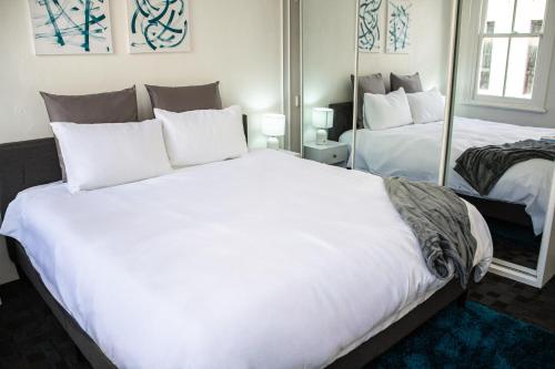 een slaapkamer met een groot wit bed en spiegels bij Cozy City House in the Heart of Paddington in Sydney