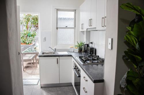 a white kitchen with a sink and a stove at Cozy City House in the Heart of Paddington in Sydney