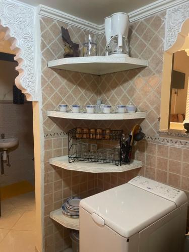 a small kitchen with a white refrigerator and shelves at Riad Nour Resorts-Riad Nour Travel in Marrakech