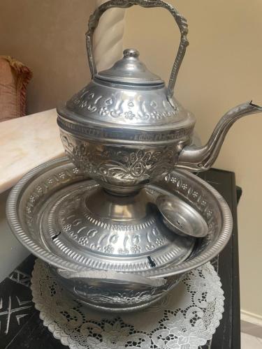 a silver tea pot on a plate with spoons at Riad Nour Resorts-Riad Nour Travel in Marrakech