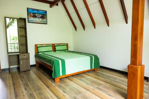 a bedroom with a bed and a wooden floor at Ever Top Resort Kithulgala in Kitulgala