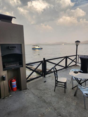 a patio with a table and chairs and a boat in the water at Le Bamboo Guest House And Boat Cruise in Hartbeespoort