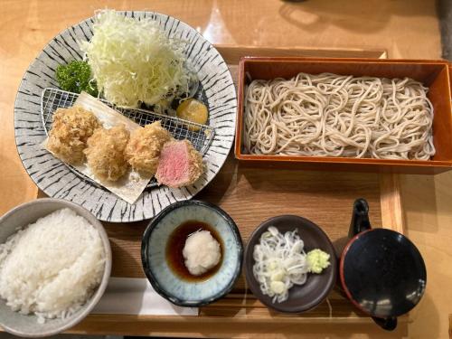 a table with plates of food and bowls of noodles at Etoile Kagurazaka-Queen Room near Shinjuku, Self Check-in in Tokyo