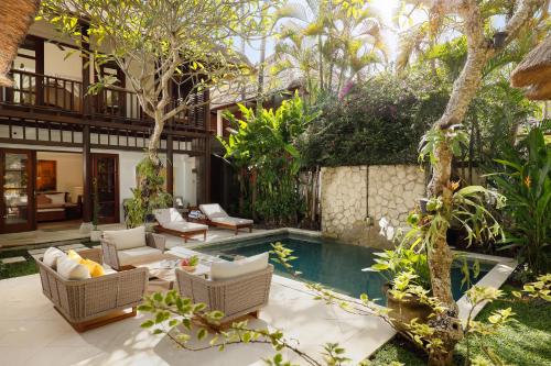a backyard with a pool and chairs and a house at Jimbaran Beach Villas by Nakula in Jimbaran