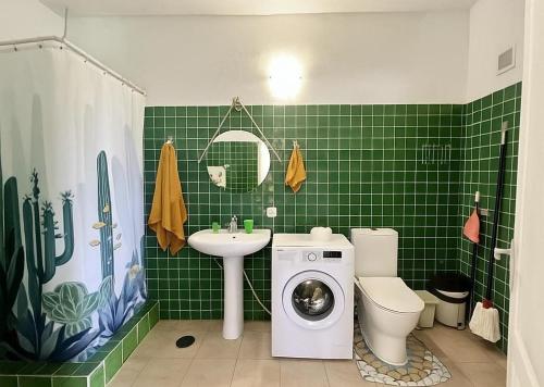 y baño de azulejos verdes con lavadora. en Happy Home, en Garachico