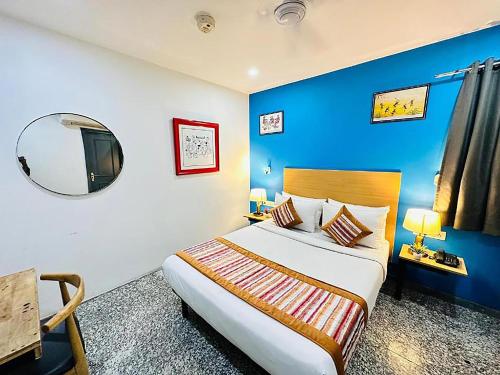 a bedroom with a large bed with a blue wall at Qotel Comfort Golden Saffron Punjabi Bagh in New Delhi