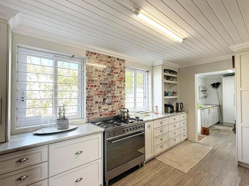 a kitchen with a stove and a brick wall at StruisHuis in Struisbaai