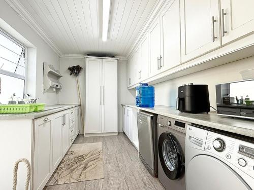 a kitchen with white cabinets and a washer and dryer at StruisHuis in Struisbaai