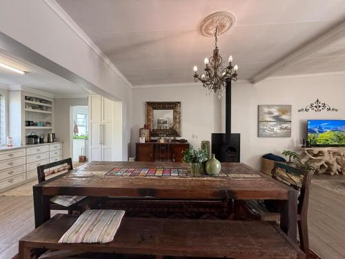 a dining room with a wooden table and a chandelier at StruisHuis in Struisbaai