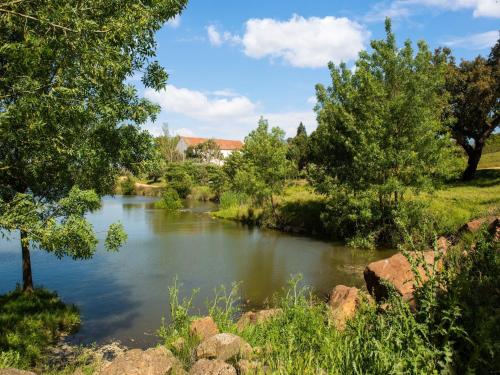 a river with trees and a house in the background at Your Montemor-o-Novo Mansion Escape in Montemor-o-Novo
