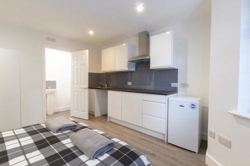 a kitchen with white cabinets and a checkered bed at Radstock Road - Room 2b in Southampton