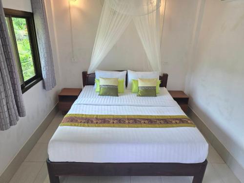 a bedroom with a large white bed with green pillows at Malulee KhaoSok Resort in Khao Sok