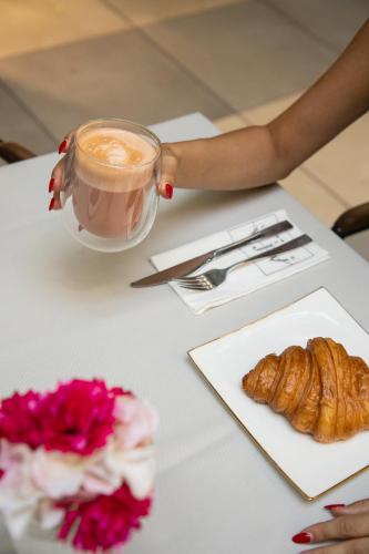 a table with a cup of coffee and a pastry at Hotel Afa in Pristina